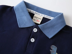 Detailed view of kids navy polo shirt featuring cartoon dinosaur embroidery on the chest