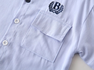 Close-up of light blue cotton shirt with detailed letter B embroidery and pocket