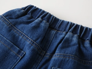 Macro shot of boy's denim jeans featuring elastic waistband and orange stitching detail