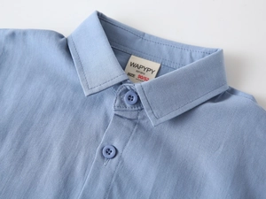Gros plan du col d'une chemise en coton bleu clair avec coutures et boutons soignés