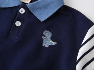 Close-up of baby boy polo sweatshirt featuring dinosaur embroidery and striped sleeves