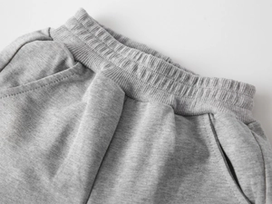Détail du jogging gris pour enfant montrant la taille élastique et la texture des poches