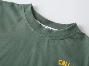 Dettaglio del girocollo a costine e della stampa gialla CALI sulla t-shirt in cotone verde