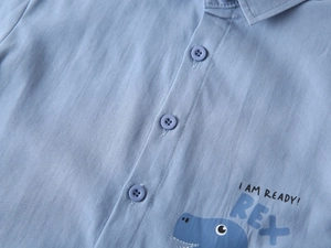 Détail de chemise bleue en coton pour enfant avec motif dinosaure et texte I AM READY