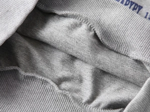 Détail des poignets côtelés et des coutures sur un sweat en coton gris chiné avec logo bleu