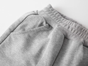 Détail de la taille élastique et de la poche latérale du pantalon de sport gris