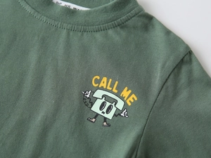 Dettaglio del tessuto in cotone e della stampa a fumetti sulla t-shirt da ragazzo verde scuro