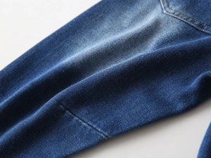 Detailed close-up of dark blue denim fabric with natural wash and stitching for boy's jeans