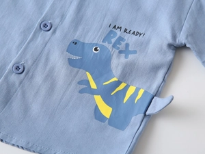 Détail d'une chemise bleue enfant avec applique queue de dinosaure 3D et texte