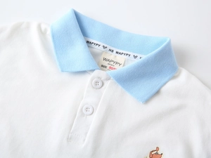 Détail du col d'un polo blanc avec bordure bleue et écusson de chien mignon brodé
