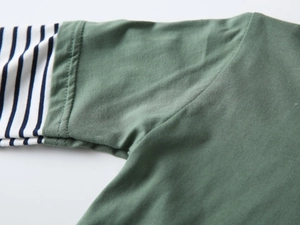 Dettaglio della maglietta a maniche lunghe verde oliva con maniche a righe bianche e nere