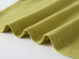 Détail du tissu en maille vert olive montrant des coutures doubles et une texture fine