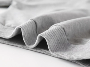 Gros plan sur le tissu gris clair d'un sweat avec texture côtelée et finition coton doux