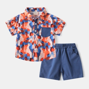 Flat lay of boys' summer set with multi-color abstract print shirt and navy blue shorts