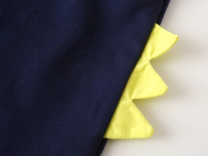Détail du décor dinosaure jaune sur tissu en maille bleu foncé de l'ensemble garçon