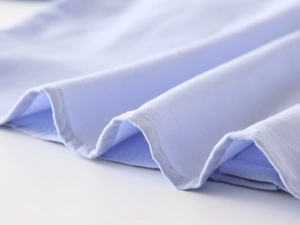 Detail of light blue cotton shirt fabric showing high-quality stitching and hem texture