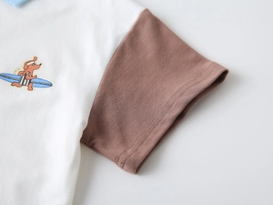 Détail d'un polo pour garçon montrant des coutures contrastées et un tissu piqué texturé