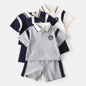 Flat lay of cotton kids polo sets featuring striped collars and bear embroidery