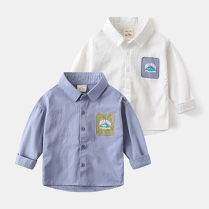 Detail of boys' cotton shirts with dinosaur embroidery and contrast pocket design