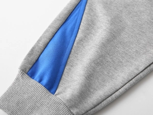 Gros plan détaillé des poignets côtelés gris avec empiècement bleu sur pantalon enfant