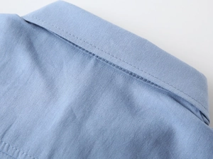 Gros plan du col de chemise bleu clair pour garçon avec couture nette et texture sergée