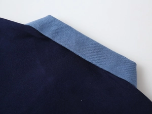 Detail of boys' polo shirt featuring contrasting navy body and light blue ribbed collar