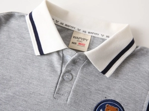 Close-up of boys gray polo shirt collar with navy stripes and bear embroidery detail