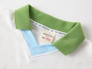 Close-up of boys white polo shirt featuring green ribbed collar and branded inner neck tape