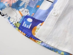 Détail d'une chemise enfant imprimée avec coutures soignées, bouton blanc et motifs cartoon