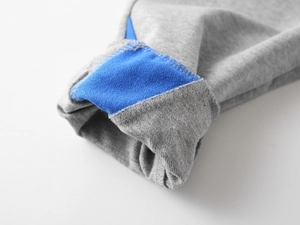 Détail macro des coutures contrastées gris et bleu royal sur le pantalon de sport enfant