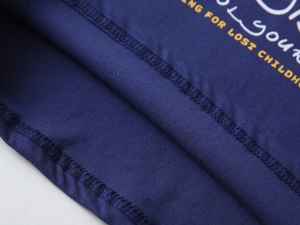 Gros plan détaillé de l'ourlet à double couture et des motifs sur t-shirt bleu marine