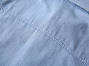 Détail du tissu en coton bleu clair avec coutures renforcées à double aiguille de qualité