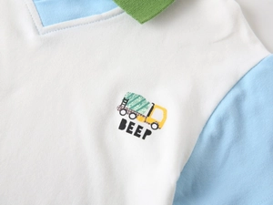 Detail of boys' polo shirt showing a cartoon truck embroidery and green contrast collar