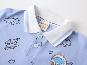 Detailed view of kids blue polo shirt with dinosaur print and premium cotton texture