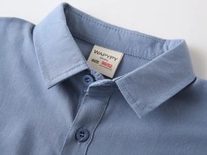 Close-up of blue cotton shirt collar with buttons and WAPYPY brand label detail