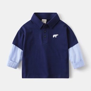 Detail of navy blue kids polo shirt featuring a polar bear embroidery and striped sleeves