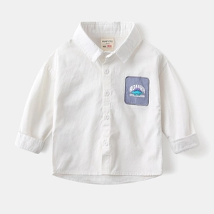 Detail of white cotton boy's shirt featuring a purple dinosaur patch on the chest pocket