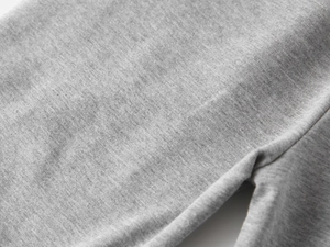 Gros plan sur la texture du tissu en tricot gris chiné des pantalons de sport pour enfants