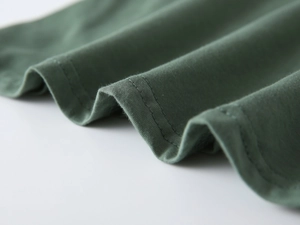 Dettaglio della cucitura a doppio ago su maglia di cotone verde scuro per t-shirt bimbo