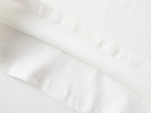 Macro detail of the neat hemline stitching on white cotton fabric for boys' polo shirt