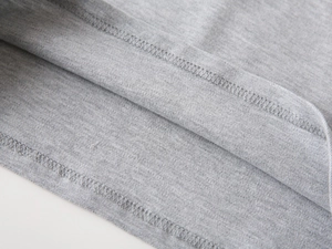 Detail of grey knitted fabric texture and precise double-needle stitching on the hem
