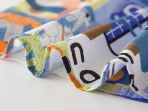 Détail du tissu d'une chemise garçon avec imprimés de dessins animés abstraits et couture d'ourlet