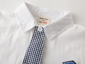 Detailed macro view of child's white shirt collar with black and white checkered tie detail