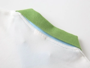 Detail of white knit polo shirt collar with green ribbing and blue inner piping