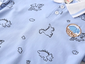 Close-up of light blue polo shirt with dinosaur prints and high-quality embroidered dino patch