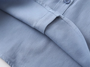 Detailed macro view of high-quality sewing and button on light blue cotton kids shirt
