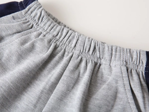 Close-up of elastic waistband on dark gray knitted shorts with navy side stitching
