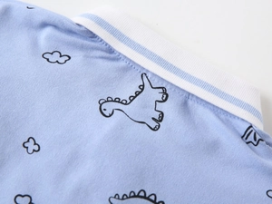 Detailed view of striped polo collar and cute dinosaur print on blue knit fabric