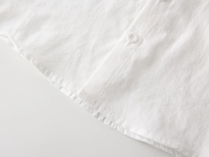 Detail view of natural cotton fabric texture and white buttons on a boy's shirt