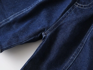Gros plan détaillé des coutures et du tissu sergé du short en denim bleu foncé pour garçon